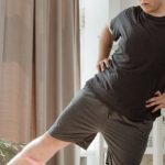 Home Workouts - Man in Black T-Shirt and Gray Shorts Doing Leg Exercises with Rubber Strength Band