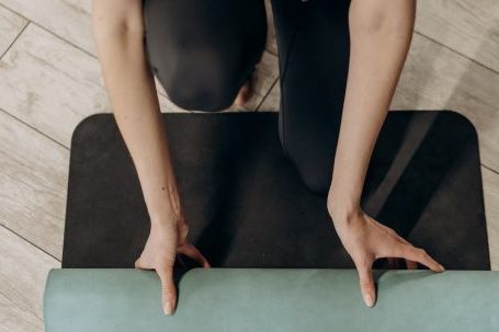 Home Exercises - Woman in Black Leggings Unrolling A Yoga Mat