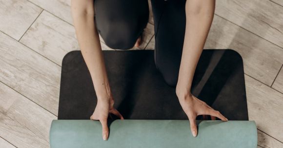 Home Exercises - Woman in Black Leggings Unrolling A Yoga Mat
