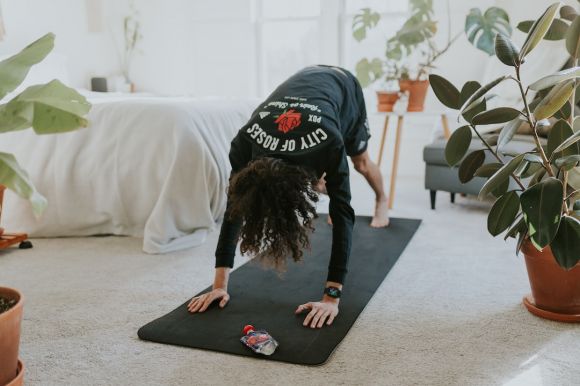 Home Workouts - a woman is doing a yoga pose on a mat