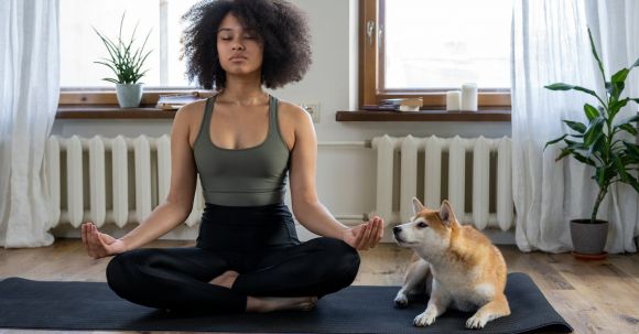 Home Fitness - Woman Doing Yoga Beside her Dog