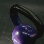 Strength Training Tools - From above of single violet kettlebell with handle for weight training on black background