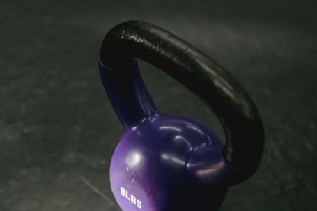 Strength Training Tools - From above of single violet kettlebell with handle for weight training on black background