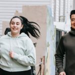 Cardio Confidence - Happy fit ethnic man and obese woman jogging together on city street