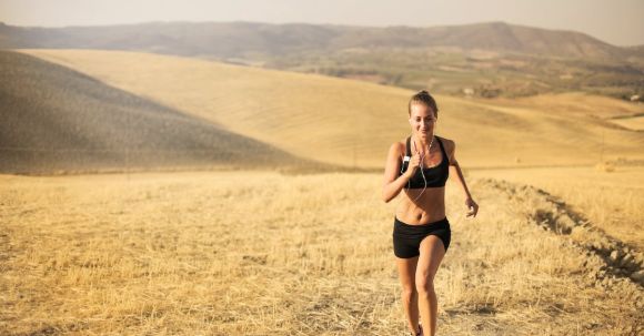 Cardio Workouts - Happy young woman running in field
