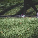 Fitness Exercises - shallow focus photography of person walking on road between grass