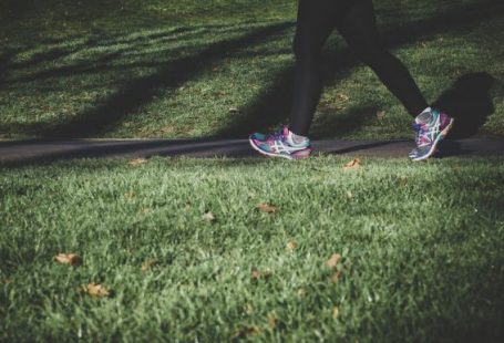 Fitness Exercises - shallow focus photography of person walking on road between grass