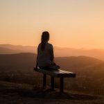Meditation - woman sitting on bench over viewing mountain