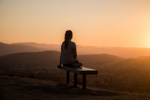 Meditation - woman sitting on bench over viewing mountain