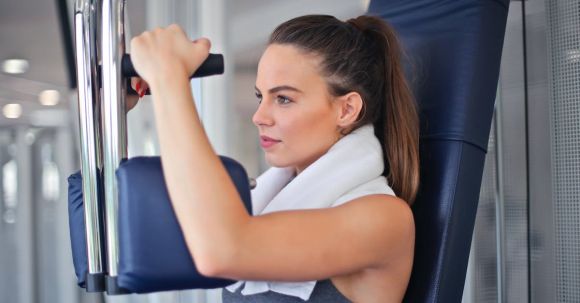 Weight Loss Secret - Young determined sportswoman doing exercise on weight machine in modern sports club