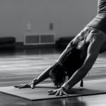 Yoga - woman in black tank top and black pants bending her body on floor