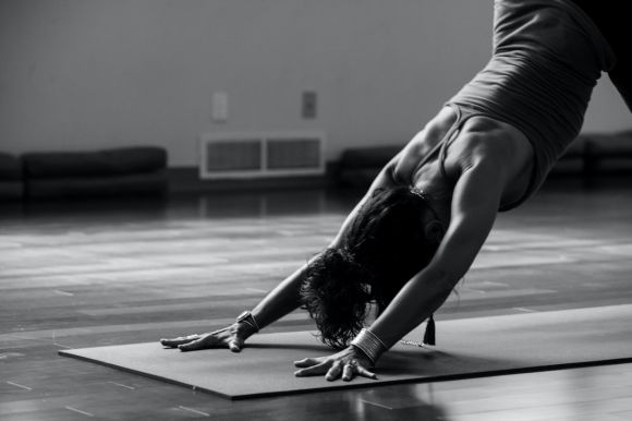 Yoga - woman in black tank top and black pants bending her body on floor
