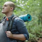 Weight Loss Journey - Male plump backpacker with hiking equipment in woods