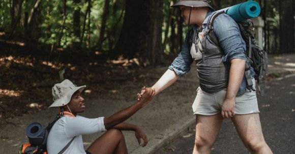 Fitness Journey - Hiker holding hand of black friend on road