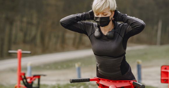 Abs & Glutes Success - Young woman in protective mask doing hyperextension exercise outdoors
