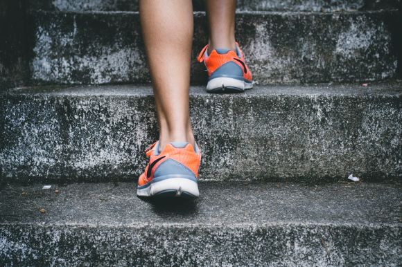 Fitness Exercises - person wearing orange and gray Nike shoes walking on gray concrete stairs