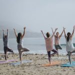 Yoga - five woman standing on seashore