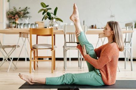 Flexibility And Mobility - Woman in Brown Sweater and Green Pants Sitting on Black Yoga Mat
