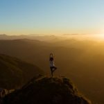 Yoga - woman stretching on mountain top during sunrise