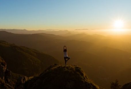 Yoga - woman stretching on mountain top during sunrise