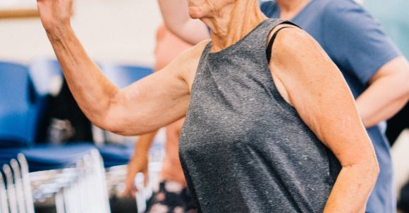 Senior Fitness - Elderly Woman in Gray Tank Top and Leggings Exercising