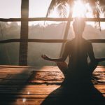 Yoga - woman in black tank top sitting on brown wooden dock during daytime