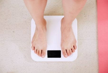 Weight Loss - person standing on white digital bathroom scale