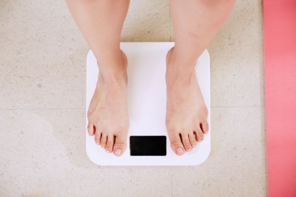 Weight Loss - person standing on white digital bathroom scale