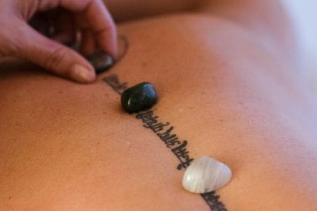 Rest, Recovery. - Crop masseuse putting stones on back of client