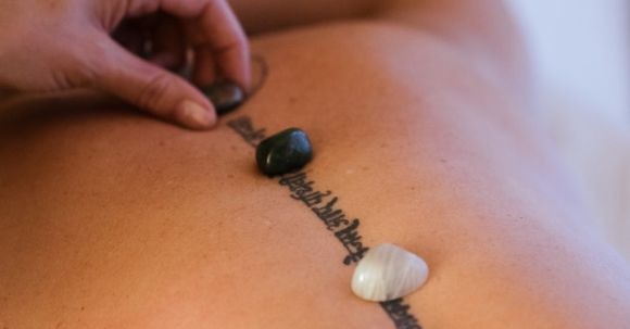 Rest, Recovery. - Crop masseuse putting stones on back of client