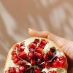 Antioxidant Importance - Crop woman demonstrating ripe pomegranate