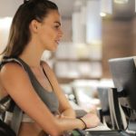 Desk Fitness - Fit smiling sportswoman waiting at gym reception desk