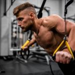 Workouts - topless man in black pants holding black and yellow exercise equipment