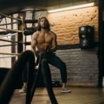 Athletic Enhancement - Man in Black Pants and Black Tank Top Standing on Brown Wooden Floor